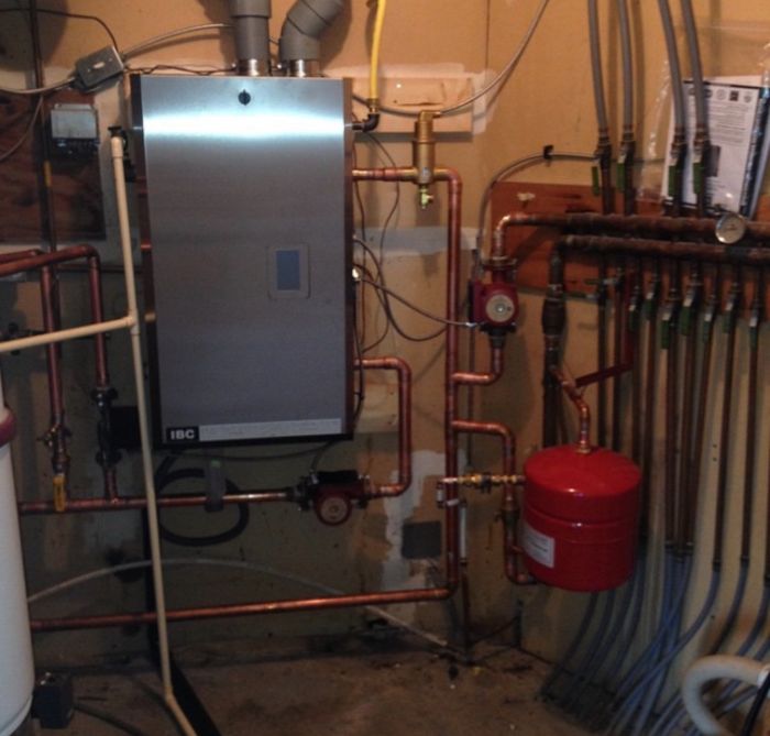 Residential boiler and radiant heating system installation with copper piping and zone valves for hydronic heating.